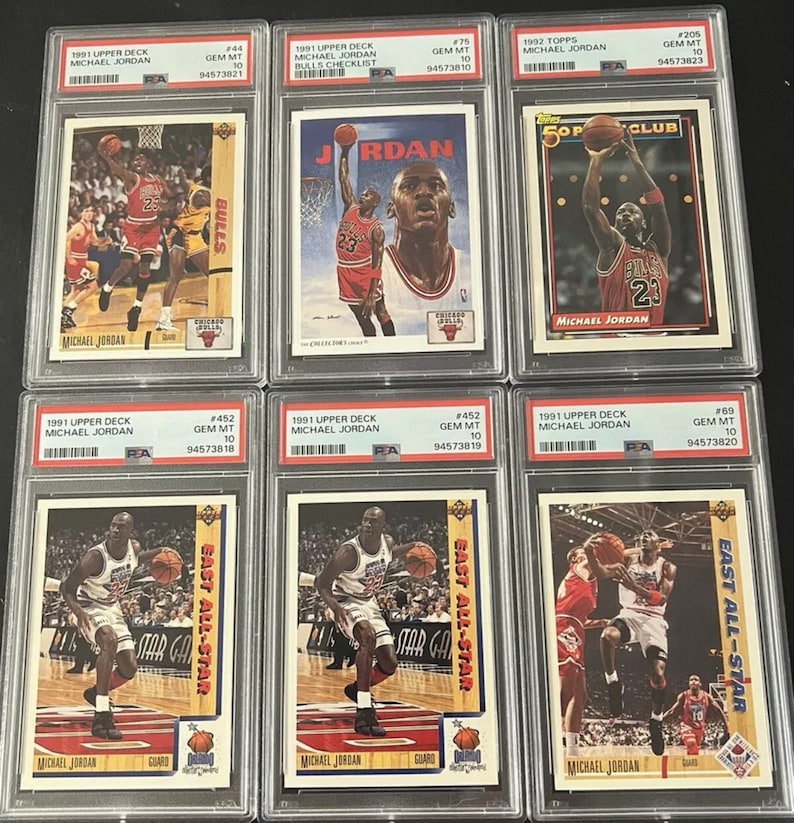 May include: A collection of ten Michael Jordan basketball trading cards from the 1991 Upper Deck, 1992 Topps, and 1991 Upper Deck East All-Star series. The cards feature images of Michael Jordan in his Chicago Bulls uniform and his East All-Star uniform. The cards are graded GEM MT 10.