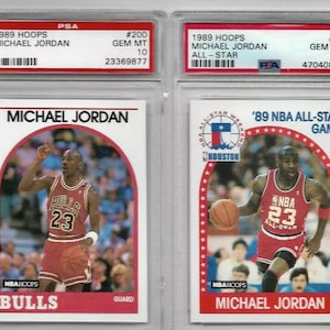 May include: Two graded trading cards of Michael Jordan from the 1989 Hoops series. The card on the left shows Jordan in his Chicago Bulls uniform, while the card on the right shows him in his 1989 NBA All-Star Game uniform. Both cards are graded Gem Mint 10 by PSA.