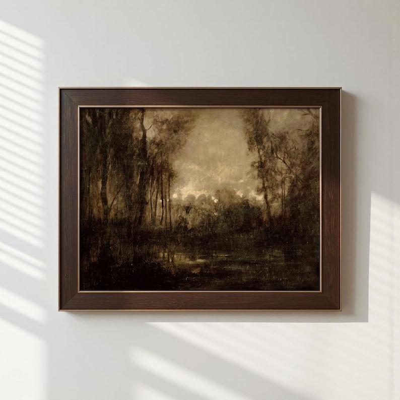 May include: A rectangular landscape painting in a dark brown wooden frame. The artwork depicts a moody, monochromatic forest scene with tall trees and a reflective body of water in sepia tones, featuring soft light filtering through the dense canopy.