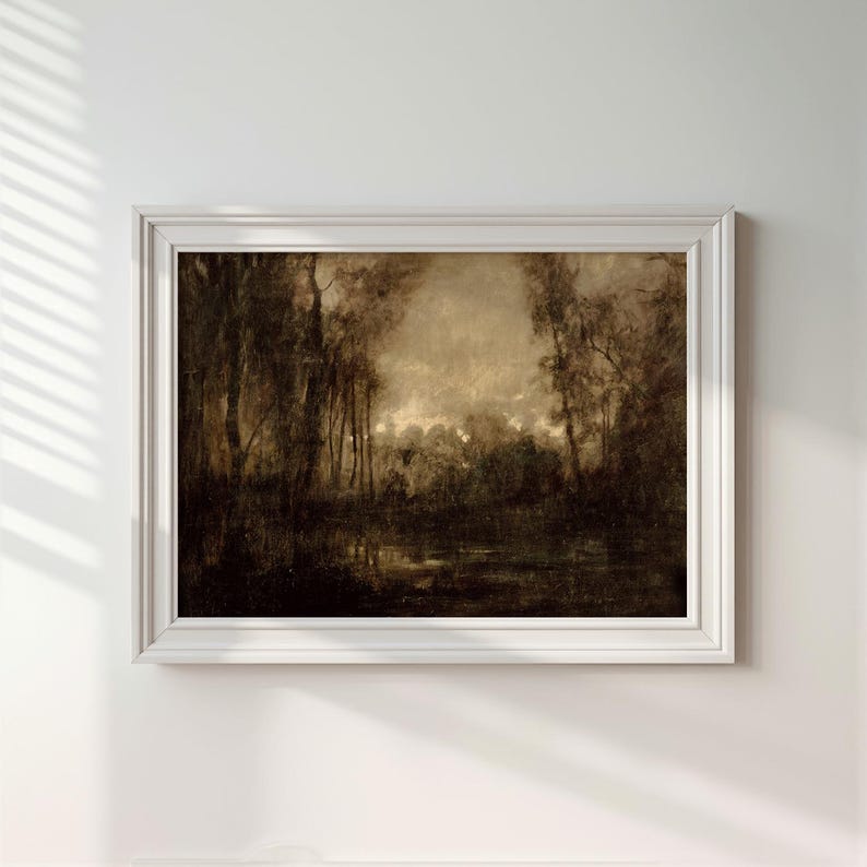 May include: A framed landscape painting in sepia tones depicting a dense forest with tall trees and a dark, reflective body of water in the foreground. The artwork is enclosed in a simple, white rectangular frame with a clean, molded edge profile.