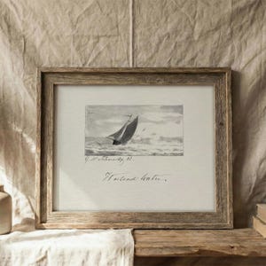 May include: A framed monochrome print of a sailboat at sea. The artwork is in a wooden frame. The image shows a sailing boat on rough water. The print includes the text "Holland water."