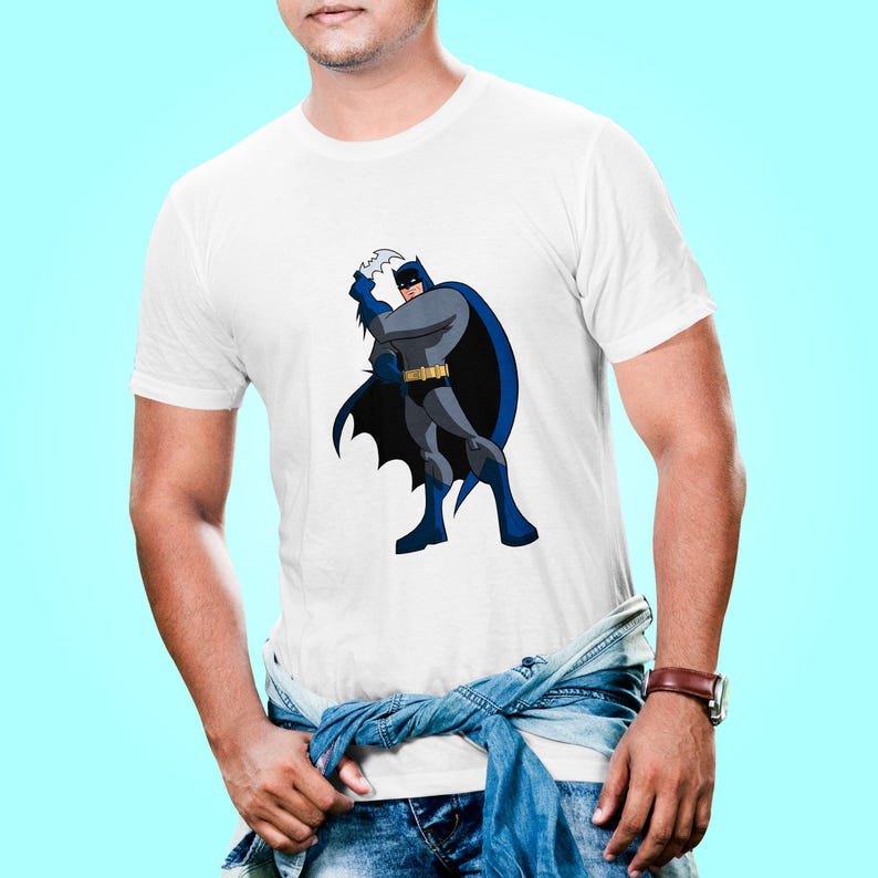 K&ouml;nnte beinhalten: Wei&szlig;es T-Shirt mit einem Cartoon-Bild von Batman in einem blauen Umhang und einem schwarzen Anzug, der einen Batarang wirft.