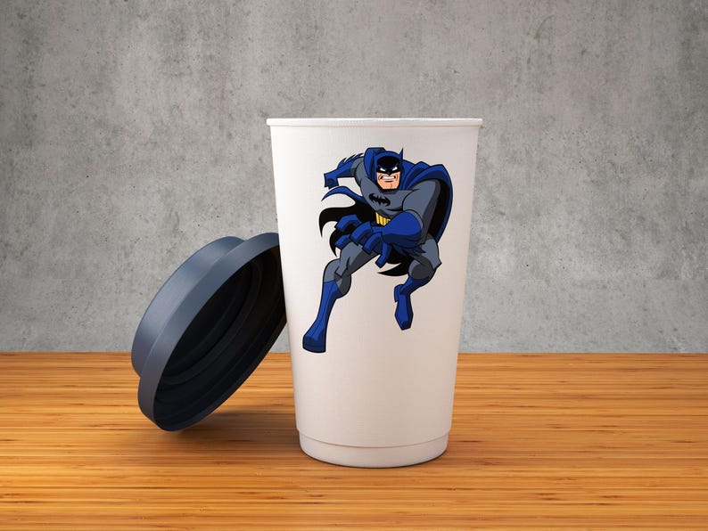 K&ouml;nnte beinhalten: Eine wei&szlig;e Reise-Tasse mit einem blauen und grauen Cartoon-Bild von Batman auf der Vorderseite. Die Tasse hat einen dunkelblauen Deckel.