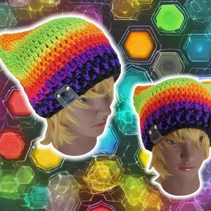 Peut inclure: Deux bonnets en crochet arc-en-ciel avec des accents noirs. Un bonnet a des oreilles de chat. Les deux bonnets ont un patch en cuir noir avec un clou argenté.