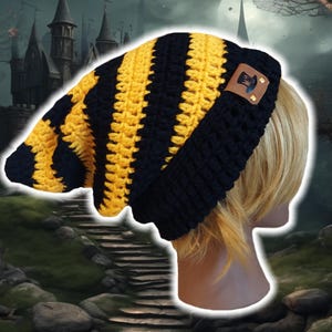 Peut inclure: Bonnet en crochet rayé noir et jaune avec une petite plaque en cuir marron qui dit "The Hat".