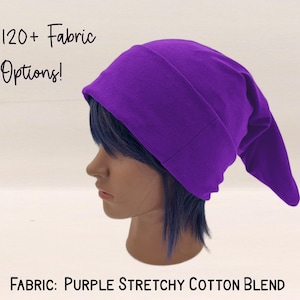 May include: A deep purple beanie hat with a pointed end, crafted from a stretchy cotton blend. The image includes the text "120+ Fabric Options!" and "Fabric: Purple Stretchy Cotton Blend".