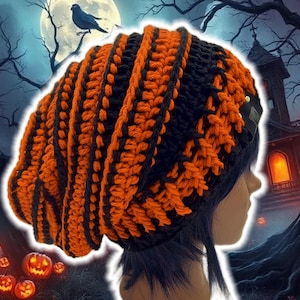 May include: A black and orange crochet beanie hat. The hat features vertical stripes of orange and black. The hat is worn by a person with dark blue hair. The background includes a spooky Halloween scene with a full moon, pumpkins, and a haunted house.