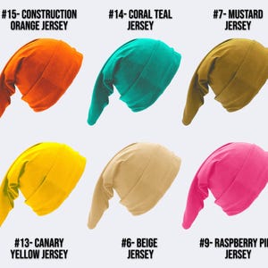 May include: Six jersey knit hats in various colors: orange, teal, mustard, yellow, beige, and raspberry pink. Each hat has a long, pointed tail. Text on the image identifies each color.