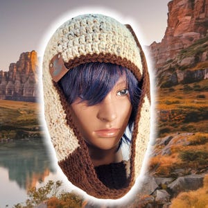 May include: A crocheted hat with ear flaps in beige and brown with a brown leather patch. The hat has a flecked texture.