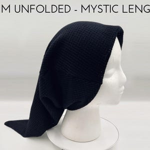 May include: A black knit hat with an unfolded brim and a long, pointed tail, displayed on a white mannequin head. The text BRIM UNFOLDED - MYSTIC LENGTH is printed in black at the top of the image. The hat features a textured, woven pattern.