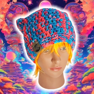 May include: A blue and pink crocheted beanie with a small black and white logo on the side. The beanie is worn on a mannequin with blonde hair.