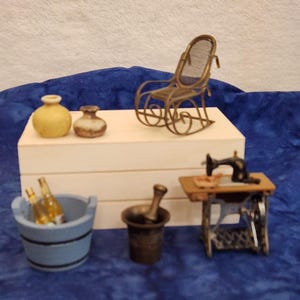 May include: A collection of miniature items including a brass rocking chair, a yellow ceramic vase, a small brown pot, a light blue bucket containing two glass bottles, a dark metal mortar and pestle, and a black vintage-style sewing machine.