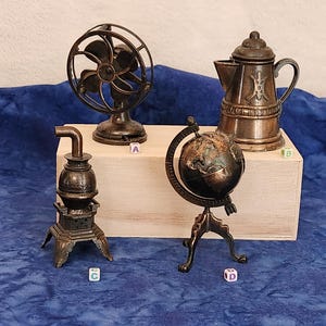 May include: Four vintage metal pencil sharpeners on a wooden surface. The sharpeners are shaped like a fan, a coffee pot, a stove, and a globe.