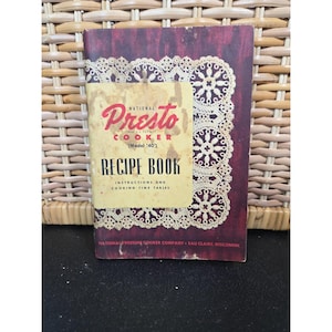 May include: A vintage "Presto Cooker" recipe book. The cover is a deep burgundy with a cream-colored label featuring the "Presto" logo in red script. The book includes instructions and cooking time tables.