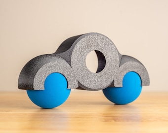 May include: A gray toy car with blue wheels. The car is made of foam and has a simple design.