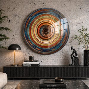 May include: A large, circular wall art piece with a glossy finish. The artwork features a vibrant, concentric design of swirling colors, including blue, orange, yellow, and red. The piece is mounted on a textured, gray concrete wall, creating a modern aesthetic.