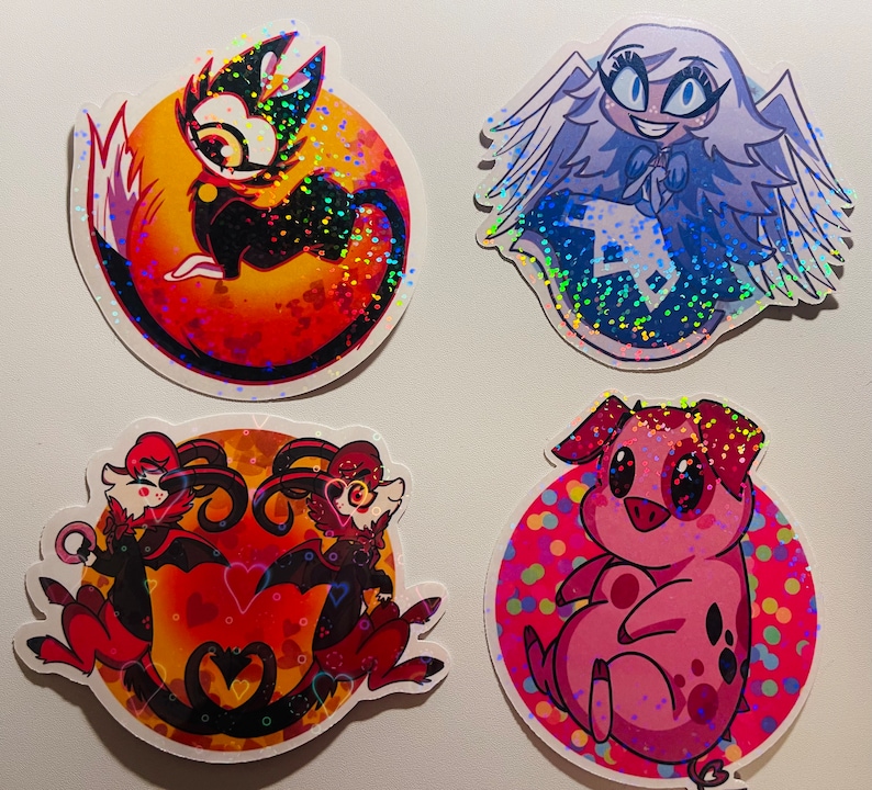 May include: Four holographic stickers featuring cartoon characters. The first sticker is a red and black cat with a yellow eye on a red background with hearts. The second sticker is a white angel with a blue dress and wings on a blue background with white dots. The third sticker is two red and black demons with horns and wings on a red background with hearts. The fourth sticker is a pink pig with a pink nose and black eyes on a pink background with colorful dots.