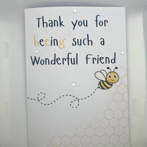 May include: A white card with black text that reads "Thank you for being such a wonderful friend." A cartoon bee with black and yellow stripes is flying over a honeycomb pattern.