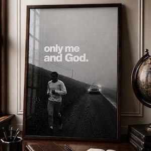 May include: A framed black and white wall art print featuring a person jogging along a dark, foggy road with a car in the distance. The text "only me and God." is printed in white in the upper portion of the image. The frame is dark wood.
