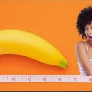Peut inclure: Une banane jaune mûre à côté d'un mètre ruban et d'une personne qui fait un clin d'œil. L'arrière-plan est orange. La personne porte un débardeur rayé blanc et rose.