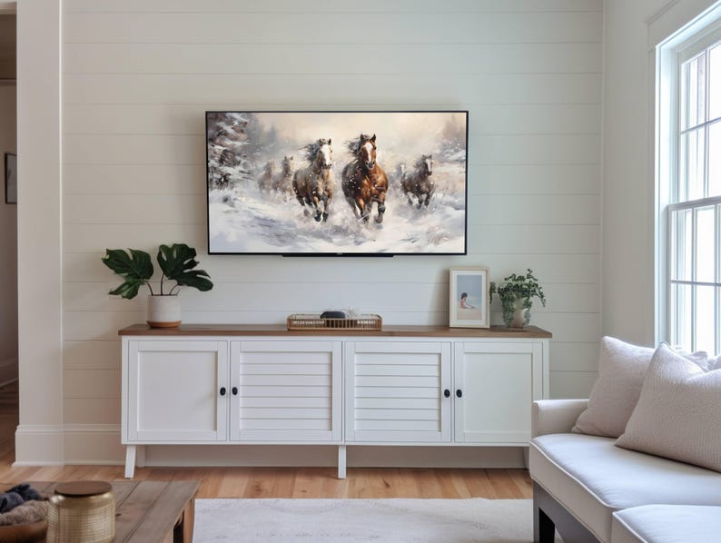 Pu&ograve; includere: Una consolle multimediale bianca con quattro ante e un piano in legno. Un televisore &egrave; montato sopra la consolle, che mostra un dipinto di cavalli che corrono attraverso un paesaggio innevato. Un piccolo quadro incorniciato &egrave; appeso al muro a destra del televisore.