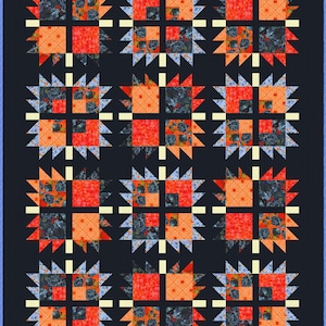 May include: A handmade quilt with a dark blue background. The quilt features a repeating pattern of orange and red squares, surrounded by starburst shapes in blue and cream. The squares have floral patterns.