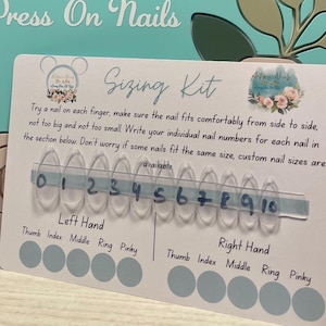May include: A teal sign with gold lettering reading "Artisan Nails By Julia Luxury Press On Nails." A "Sizing Kit" card shows clear nail samples numbered 0-10. The card includes instructions for measuring nail sizes.