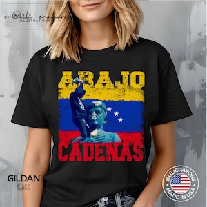 May include: Black t-shirt with a graphic design featuring a person breaking free from chains, a Venezuelan flag, and the text "ABAJO CADENAS".