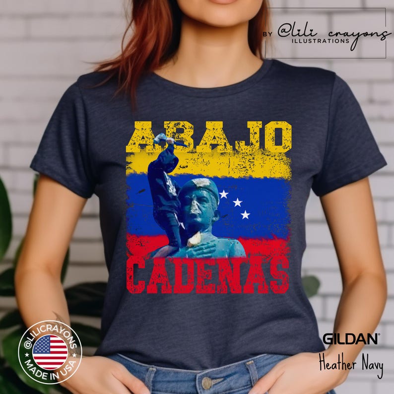 May include: A navy blue t-shirt with a distressed yellow and red graphic of a statue and the text "ABAJO CADENAS". The graphic also includes the Venezuelan flag.