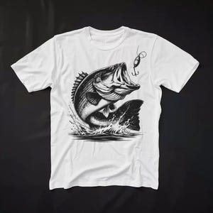K&ouml;nnte beinhalten: Wei&szlig;es T-Shirt mit einer Schwarzwei&szlig;illustration eines Gro&szlig;maulbarsches, der mit einem K&ouml;der im Maul aus dem Wasser springt.