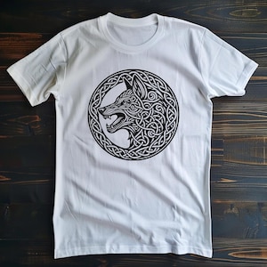 May include: White t-shirt with a black and white graphic of a wolf's head in a Celtic knot design.