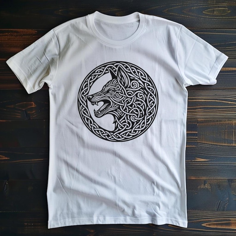 May include: White t-shirt with a black and white graphic of a wolf's head in a Celtic knot design.