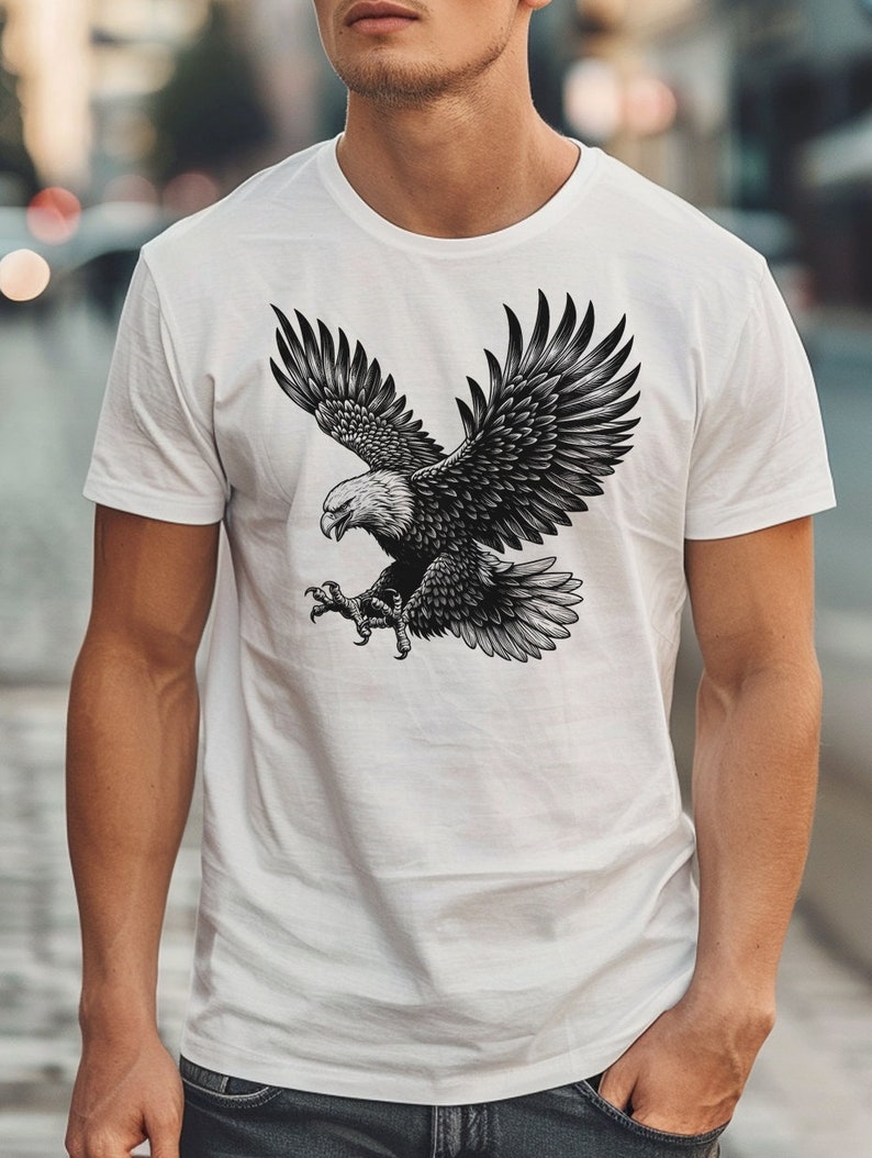 May include: A white t-shirt with a black and white illustration of an eagle in flight.