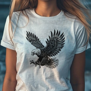 May include: A white t-shirt with a black and white graphic of an eagle in flight.