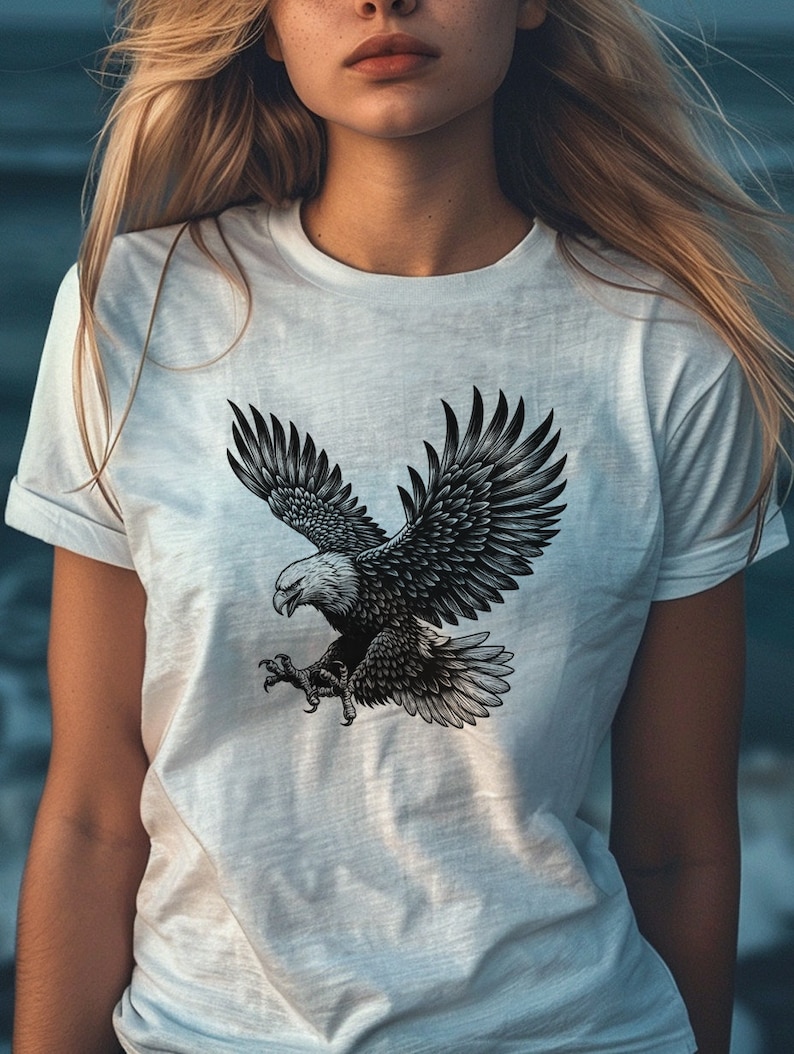May include: A white t-shirt with a black and white graphic of an eagle in flight.