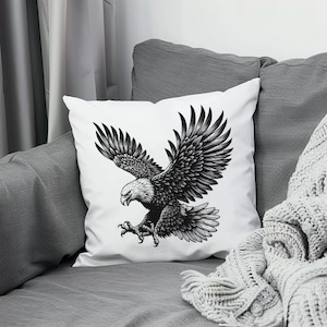 May include: A white throw pillow with a black and white illustration of an eagle in flight. The eagle is depicted with its wings spread wide and its talons extended.