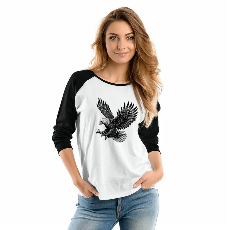 May include: A white and black baseball style long-sleeved shirt with a black eagle graphic on the front.
