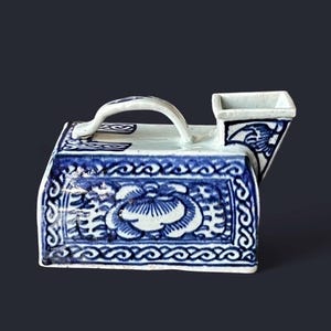 Könnte beinhalten: Ein blau-weißes Keramikgefäß mit Griff und Ausguss. Das Gefäß weist florale und geometrische Muster in Blau auf weißem Hintergrund auf. Der Griff ist gewölbt und der Ausguss ist quadratisch.