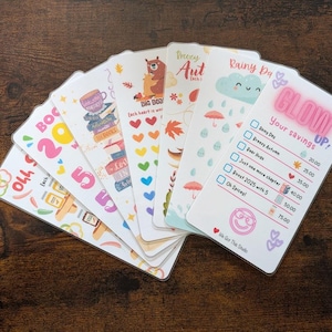 May include: A set of colourful cards with illustrations and text. The cards feature themes such as "Cozy Autumn", "Rainy Day", and "Glow Up!" with a savings tracker. The cards are designed for a planner or journal.