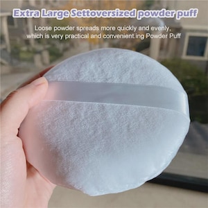 Può includere: Un piumino per cipria bianco extra large con un nastro di raso. L'immagine include il testo "Extra Large Settoversized powder puff" e "Loose powder spreads more quickly and evenly, which is very practical and convenient.ing Powder Puff."