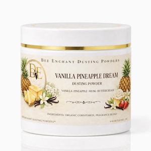 May include: A white jar of "Vanilla Pineapple Dream" dusting powder with gold accents. The label features pineapples, vanilla beans, and flowers. The ingredients include organic cornstarch and fragrance blend.
