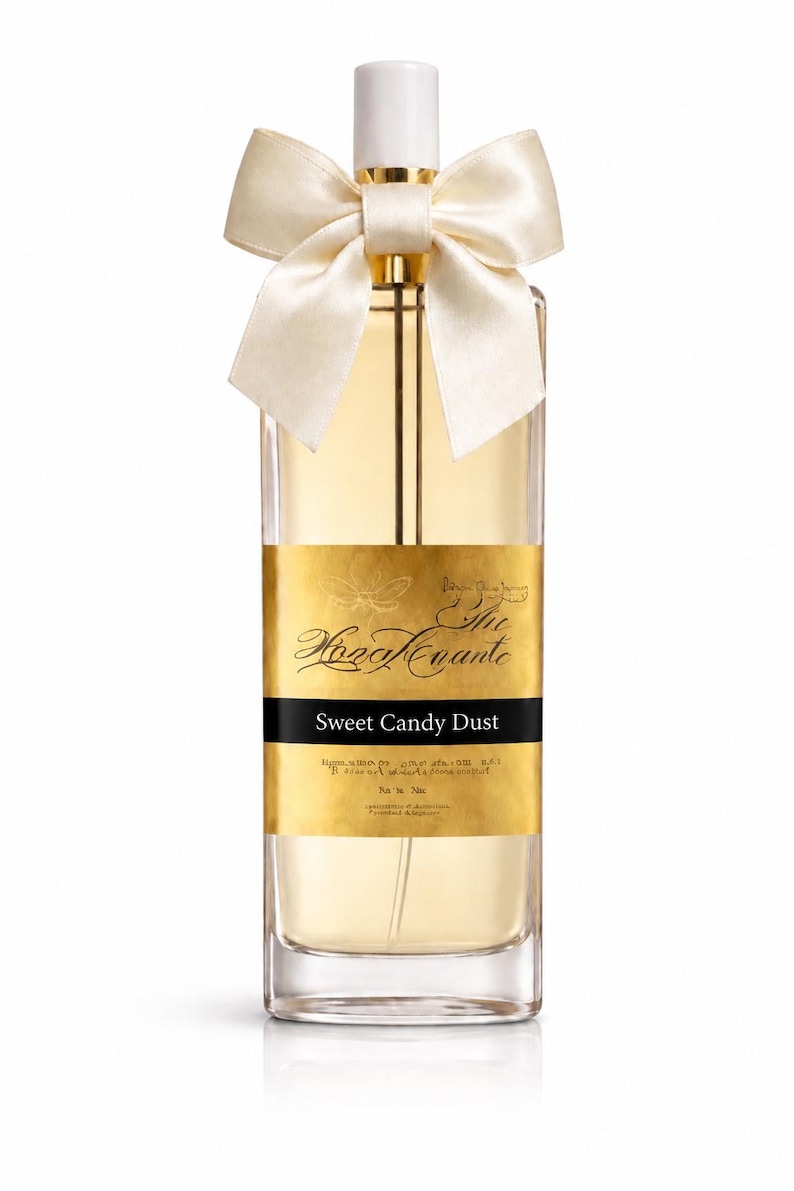 May include: A rectangular perfume bottle with a white cap and a cream-colored bow. The bottle has a gold label with the text "Sweet Candy Dust". The perfume is a light amber color.