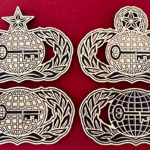 May include: Four wooden badges with a black and white design. Each badge features a globe with a key, surrounded by a wreath of leaves. The badges are on a red background.