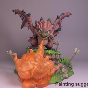 Puede incluir: Figura detallada de un dragón de dibujos animados con las alas extendidas, en tonos rosas y marrones, posado sobre una base verde con flechas. Una escultura naranja en forma de llama está en primer plano. El texto "Painting suggestion" es visible.