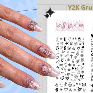 Puede incluir: Un conjunto de pegatinas para u&ntilde;as Y2K Grunge con una variedad de iconos en blanco y negro que incluyen corazones, estrellas, calaveras y personajes, junto a una hoja que muestra dise&ntilde;os de u&ntilde;as en tonos rosa con dijes met&aacute;licos.