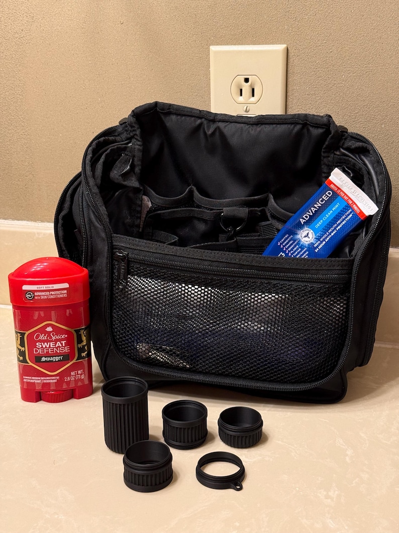 May include: Black travel bag with multiple compartments, a red and black Old Spice deodorant stick, and a tube of Advanced Deep Clean Mint toothpaste. There are also five black cylindrical objects of varying sizes.
