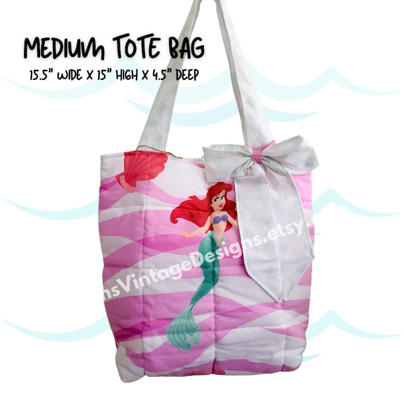 May include: A medium-sized tote bag featuring a pink and white wavy pattern with a cartoon mermaid illustration. The bag has white handles and a large bow. The bag is 15.5 inches wide, 15 inches high, and 4.5 inches deep.