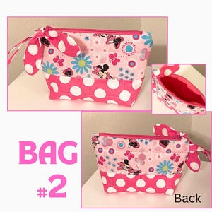 May include: Pink and white polka dot bag with a Minnie Mouse print, a pink zipper, and a bow detail. The bag has a rectangular shape and is labeled "BAG #2". The interior is pink. The back of the bag is also shown.