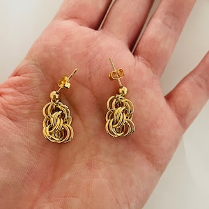 May include: A pair of gold-toned chain link earrings. The earrings are made of multiple interconnected rings.