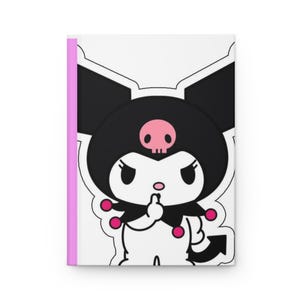 May include: A white notebook with a pink spine features a cartoon character with black ears, a black head, and a pink skull. The character is giving the middle finger. The notebook is a journal.